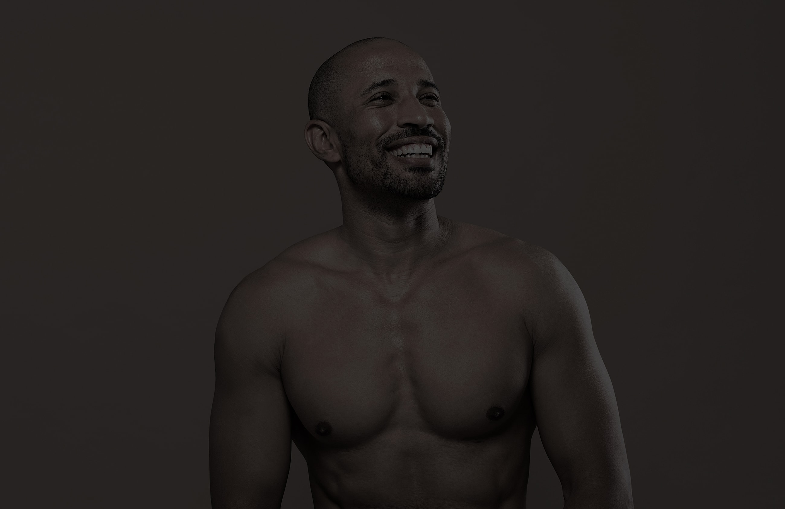 Smiling man with a muscular physique, studio portrait.