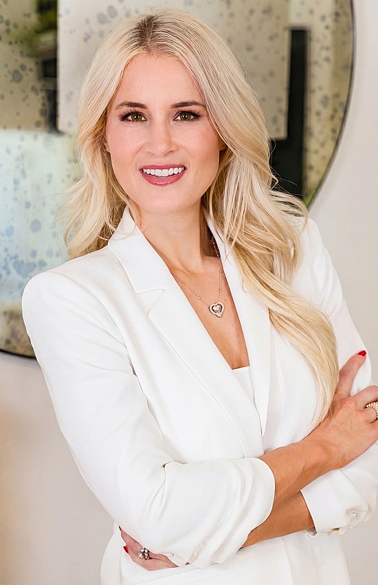 Professional woman in a white blazer smiling.