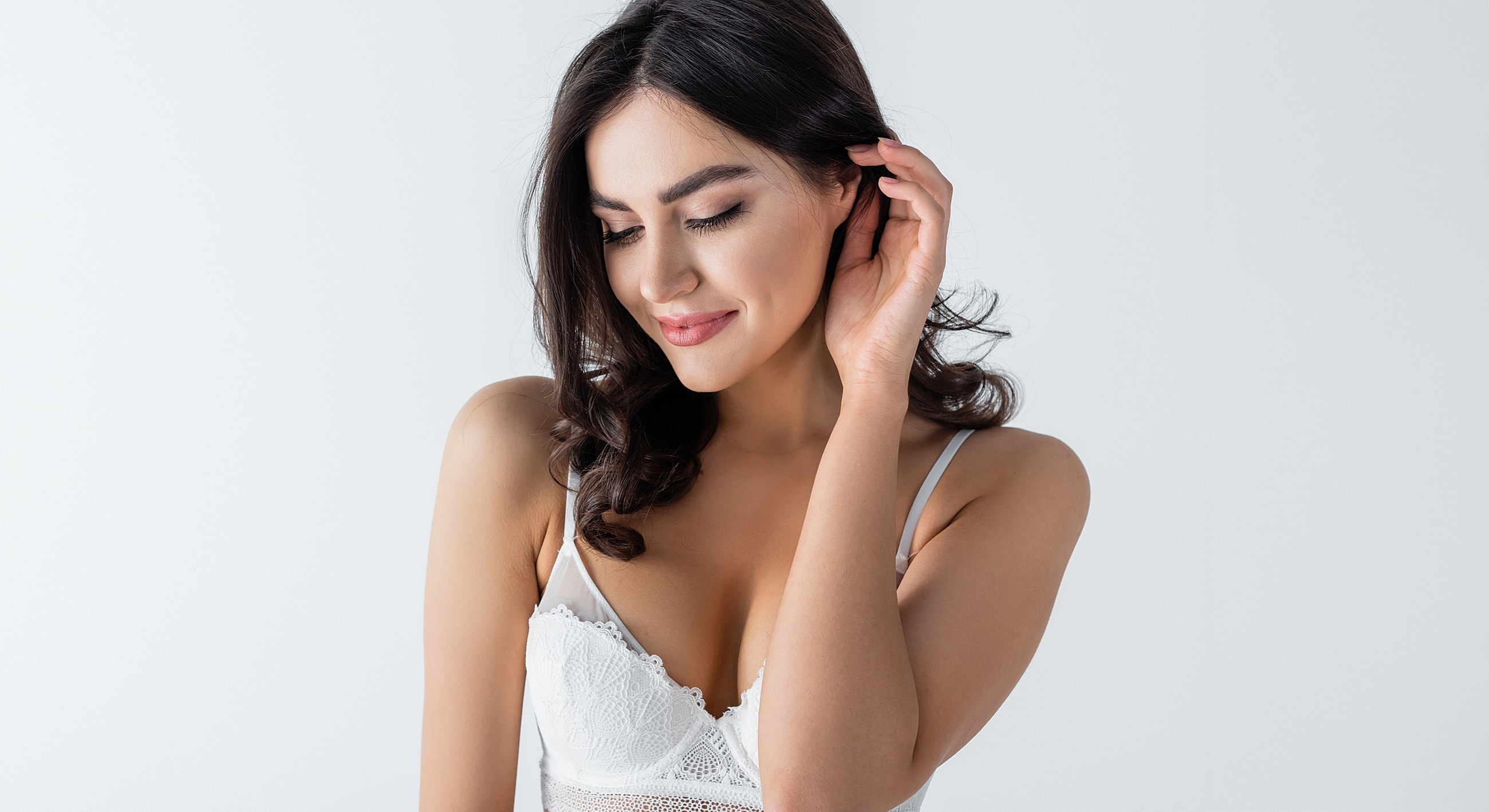 Smiling woman in white lingerie against light background