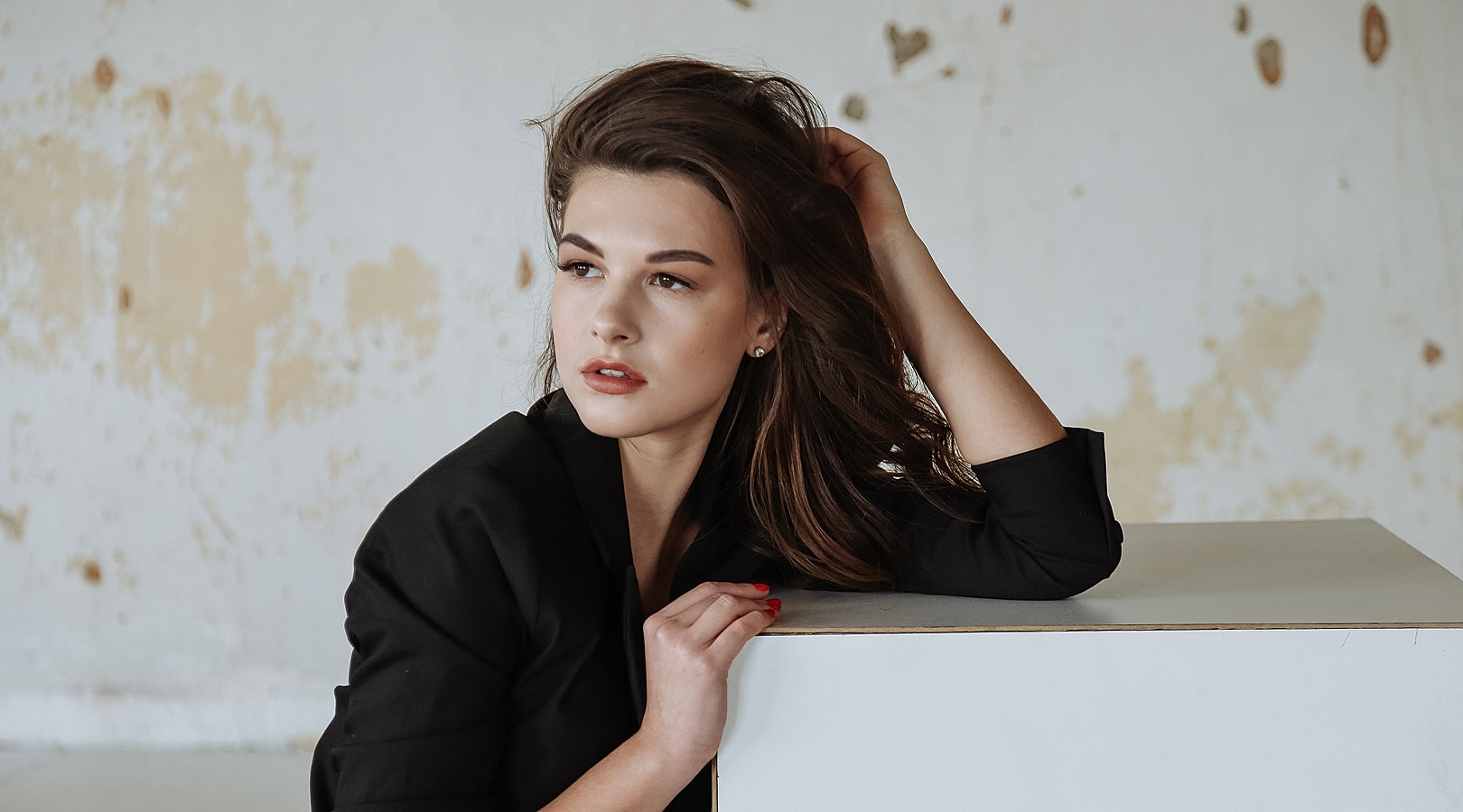 Model with long hair posing thoughtfully indoors