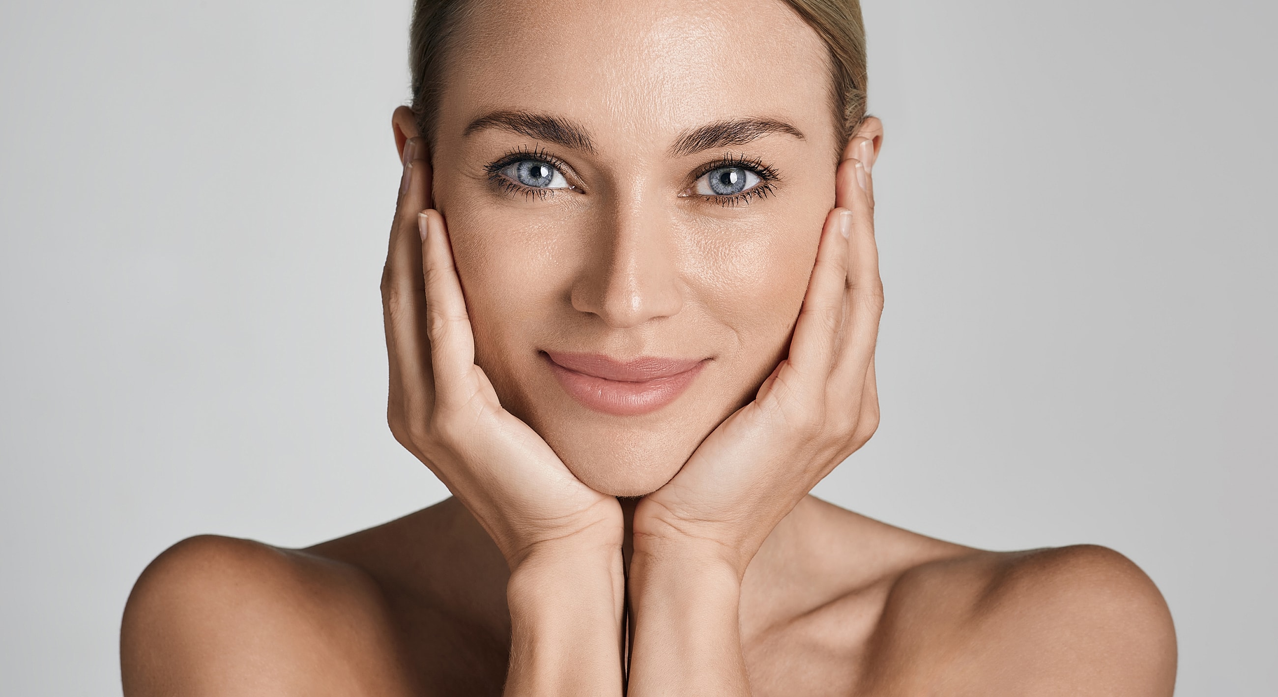 Smiling woman with clear skin and blue eyes.