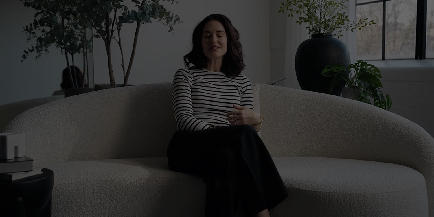 Person sitting on a stylish sofa with plants.